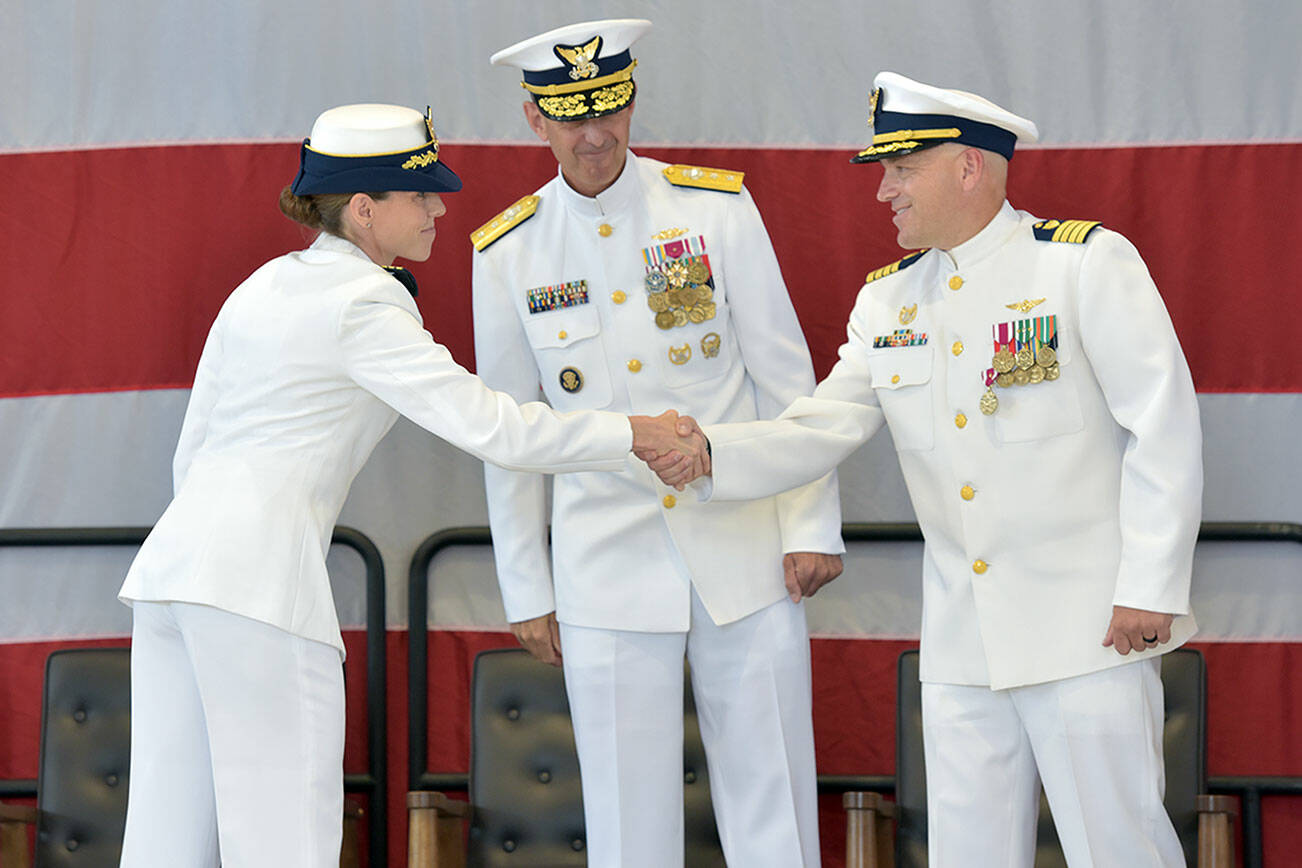 U.S. Coast Guard Cmdr. Kelly Higgins, left, shakes hands with outgoing Capt. Brent Schmadeke, right, as 13th District commander Charles Fosse looks on during Friday's change of command ceremony. Higgins will lead Air Station / Sector Field Office Port Angeles for two years after serving previously as executive officer and operations officer at Air Station San Francisco and Forward Operating Base Point Mugu in California. (Keith Thorpe/Peninsula Daily News)