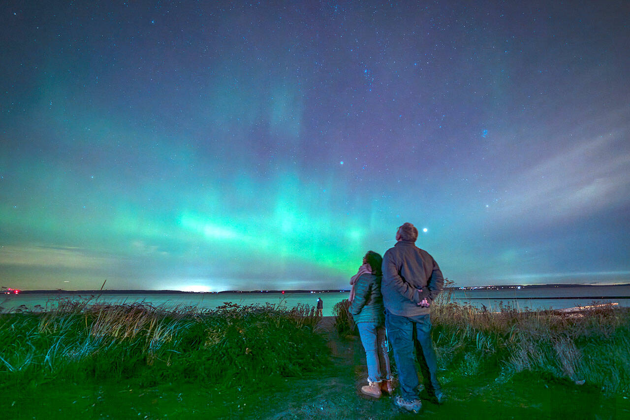 Joel Goldstein and his wife Len Maranan-Goldsmith, from Port Townsend, take in the Aurora Borealis Thursday night from the beach at Point Hudson in Port Townsend. (Steve Mullensky/for Peninsula Daily News)