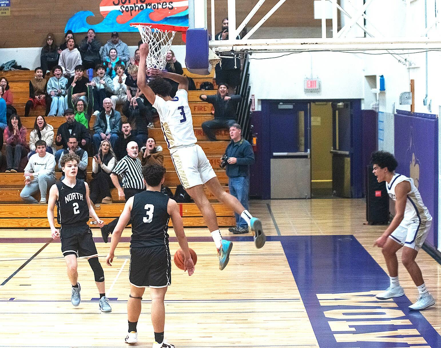Sequim’s Solomon Sheppard (3) dunks against North Kitsap on Friday as teammate Jericho Julmist, far right, celebrates. Sequim crushed the Vikings 74-46 to remain unbeaten on the season. (Emily Mathiessen/Olympic Peninsula News Group)