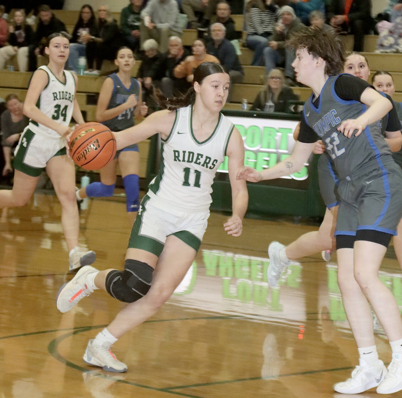 Dave Logan/for Peninsula Daily News Port Angeles’ Lindsay Smith drives to the basket and tries to get past Olympic’s Gabi McCoy during the Roughriders’ win over the Trojans on Friday. In the background is Lexie Smith (34)
