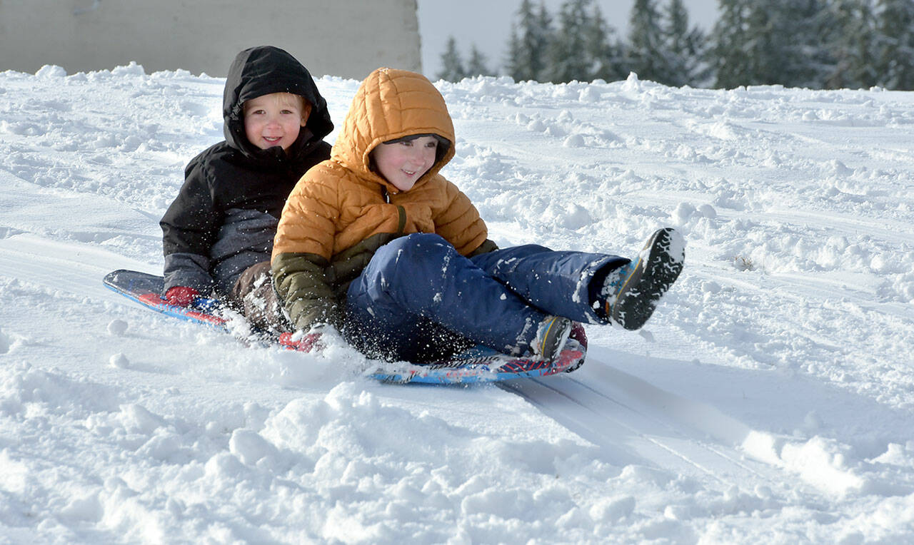 Port Angeles brothers Finley Bornsworth, 3, left, and Oliver Bornsworth, 6, take a snowy sled ride on the campus of Port Angeles High School on Tuesday. Overnight snowfall left a mantle of white over much of the North Olympic Peninsula with an additional chance of snow showers forecast through the weekend. (Keith Thorpe/Peninsula Daily News)