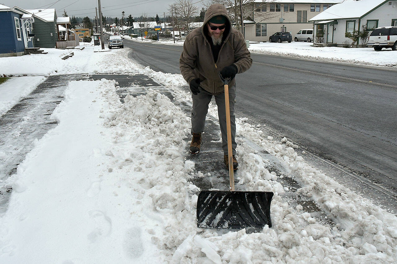 Eric Spencer, a landscaping and janitorial worker for New Life Open Bible Church, clears snow from a sidewalk next to the church at Sixth and Peabody streets in Port Angeles on Thursday morning. (Keith Thorpe/Peninsula Daily News)