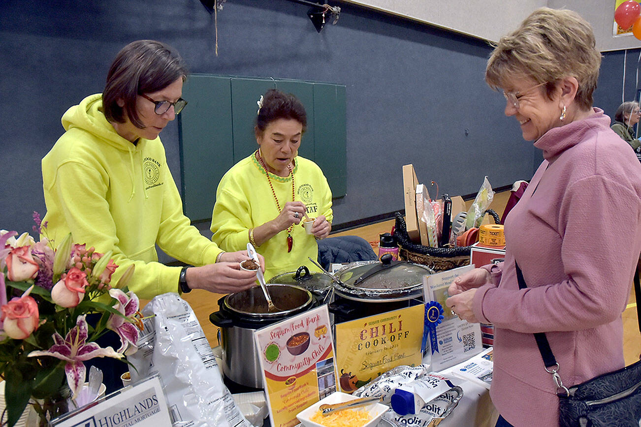 Jen Colmore, left, and June Nichols of the Sequim Food Bank serve a sample of chili to Monica Dixon of Sequim during Saturday’s Community Chili Cookoff at the Sequim Boys & Girls Club. The event, organized by the club and Boy Scout Troop 90, showcased the culinary skills of six community organizations with each group receiving a share of the proceeds and the winner taking a $500 prize. The food bank’s chili recipe took top honors in the competition. (Keith Thorpe/Peninsula Daily News)