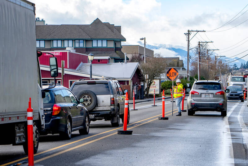 Shannon Story of Port Angeles, an employee of ACI construction in Tacoma, directs traffic on Water Street in Port Townsend on Wednesday as heavy equipment is jostled around the job site. The company is replacing a 100-year-old sewer pipeline with larger and stronger materials. (Steve Mullensky/for Peninsula Daily News)