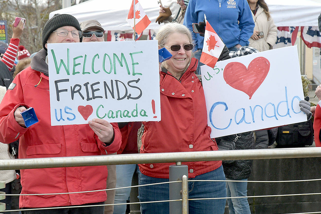 John and Deb Wallace of Sequim hold welcome signs for Canadian passengers disembarking the Coho ferry upon the resumption of daily service between Victoria and Port Angeles on Thursday. (Keith Thorpe/Peninsula Daily News)