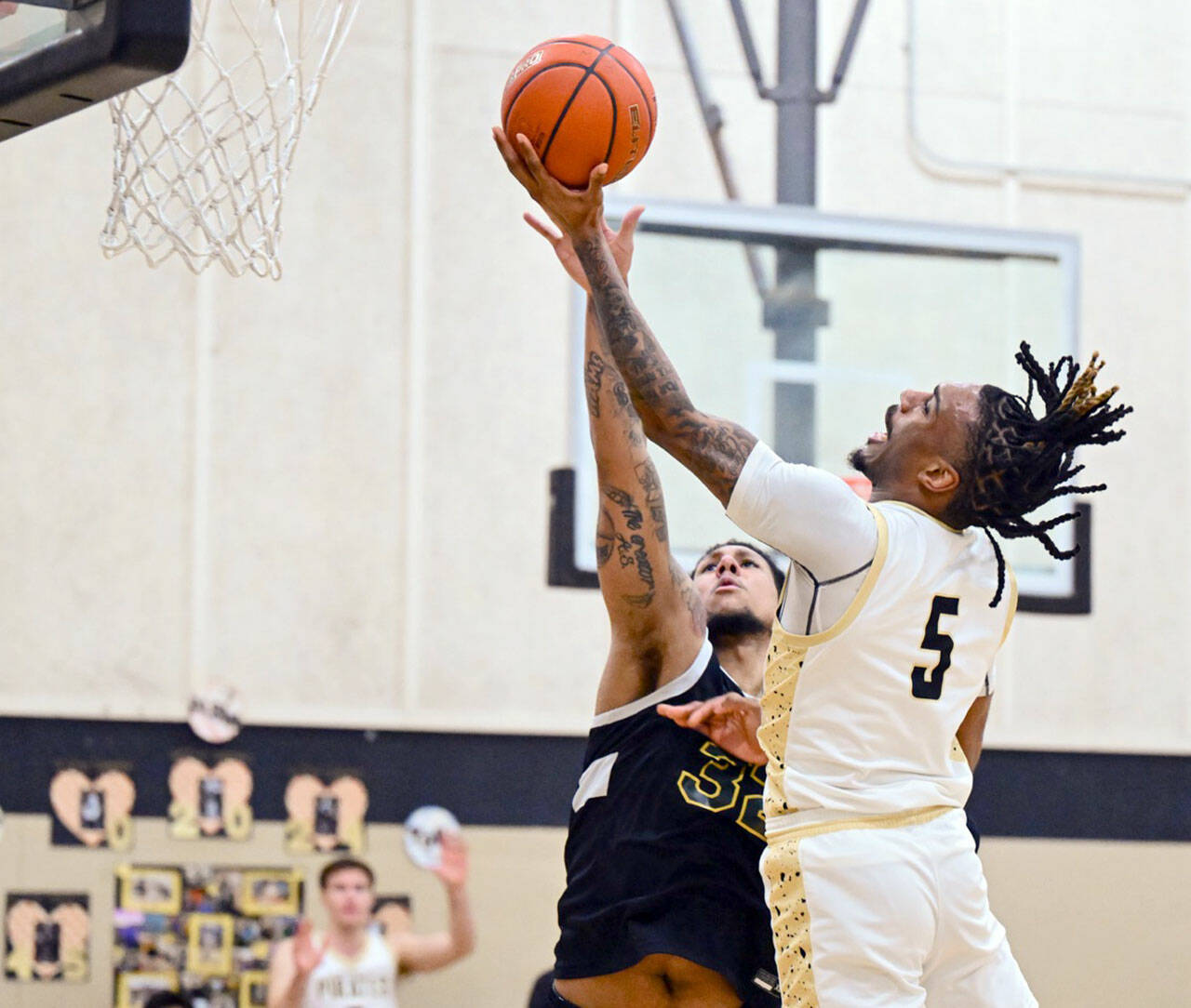 Jay Cline/Peninsula College Athletics Peninsula’s Cinco McNeal attempts a layup while defended by Shoreline’s Sherrell McCullum during the Pirates’ Sophomore Night defeat against the Dolphins.