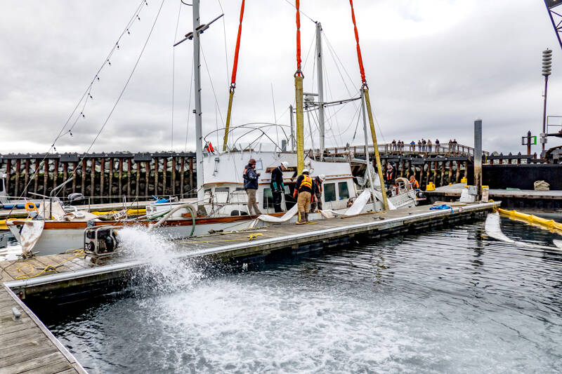 Workers from Global Diving and Salvage of Seattle pump water on Monday from inside the hull of the 50-foot powerboat Goldfinch that sank in Point Hudson Marina on Feb. 22. The boat was later towed to Port Townsend Marina. (Steve Mullensky/for Peninsula Daily News)