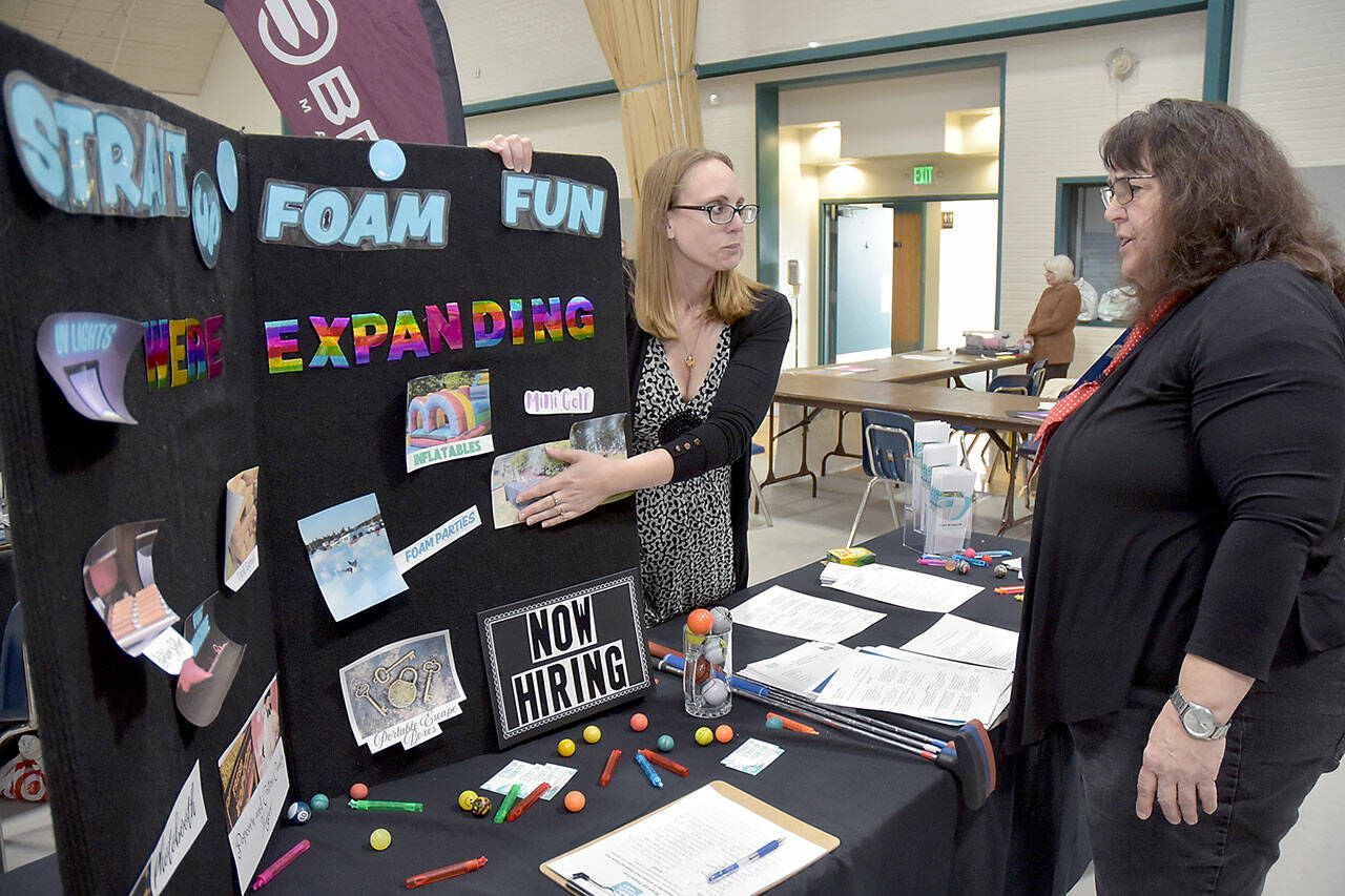 Nicole Merrigan, owner of Strait Up Foam Fun, left, talks with Carol Koenig of Sequim during Thursday’s Clallam County Job Fair at Vern Burton Community Center in Port Angeles. About two dozen prospective employers took part in the event, hosted by the Greater Port Angeles Chamber of Commerce. (Keith Thorpe/Peninsula Daily News)