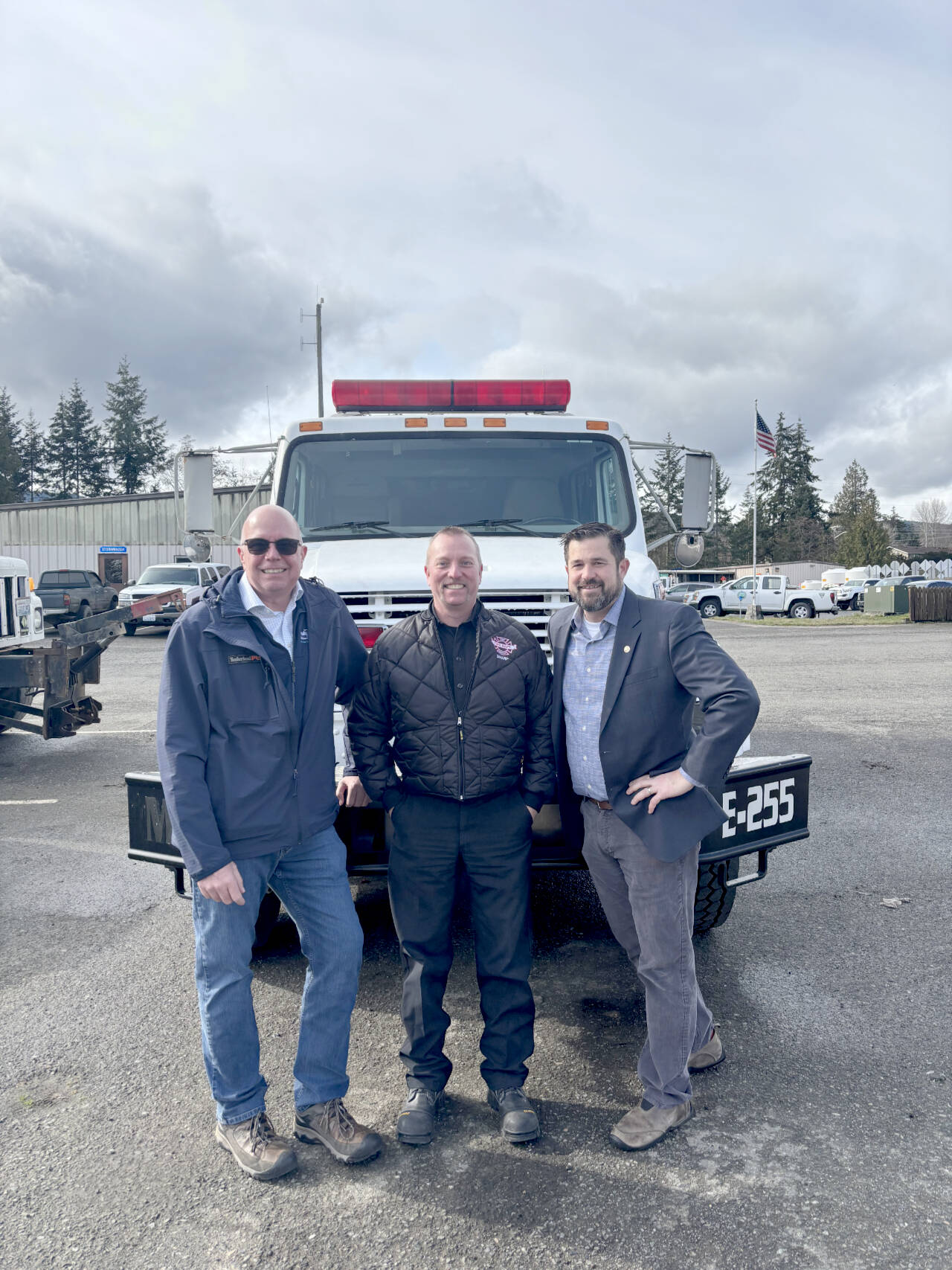 Port Executive Director Paul Jarkiewicz, left, City Fire Chief Derrell Sharp and Port Angeles City Manager Nathan West, right, pose in front of the city’s newly purchased wildland urban interface fire engine. (City of Port Angeles)
