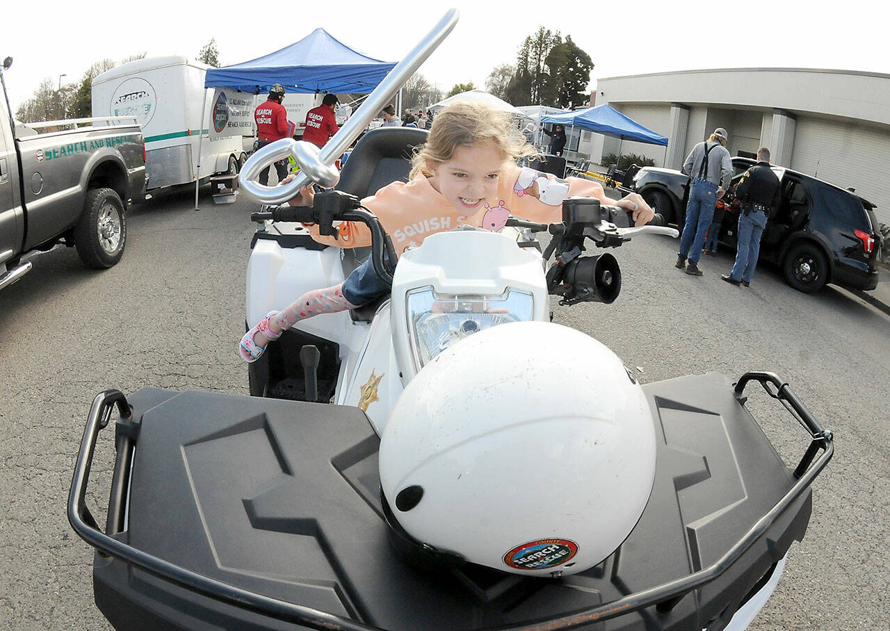 Adella Banning, 6, of Port Angeles pretends to take to the road on a all-terrain vehicle maintained by Clallam County Search and Rescue during Saturday’s Kiwanis Kids Fest at Vern Burton Community Center and a section of adjoining Fourth Street. The event featured numerous public safety displays as well as other youth activities hosted by area community service agencies. (Keith Thorpe/Peninsula Daily News)