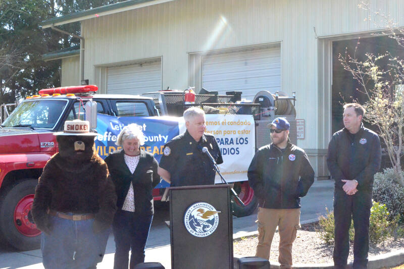 East Jefferson Fire Rescue Chief Bret Black addresses a group of attendees at the Port Ludlow fire department on Wednesday. From left to right are Smokey Bear, Jefferson County Commissioner Heidi Eisenhour, Black, Jesse Duvall, the state Department of National Resources’ Community Resilience coordinator, and EJFR Community Risk Manager Robert Wittenberg. (Elijah Sussman/Peninsula Daily News)