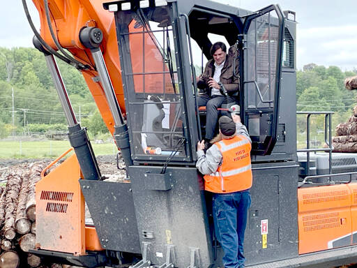 State Treasurer Mike Pellicciotti, in cab, gets guidance operating a Develon DX300LL-5 log loader on Tuesday from Port of Port Angeles log yard equipment operator Jodie O’Neel. The port purchased the $449,000 log loader through the Office of the State Treasurer LOCAL government financing program, which provides municipalities with low-cost loans for equipment and real estate purchases. Pellicciotti visited Port Angeles to talk about the LOCAL program. (Paula Hunt/Peninsula Daily News)