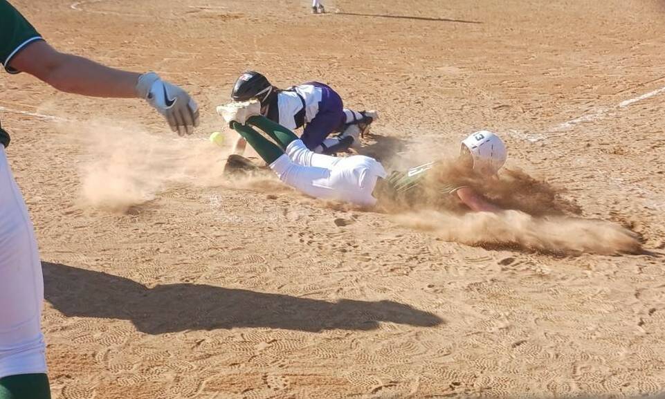 Port Angeles' Morgan Politika eats a face full of dirt as she safely slides home against North Kitsap on Thursday in a 7-0 Roughriders' win that keeps the Riders in first place in the Olympic League. In the foreground is Kennedy Rognlien. (Pierre LaBossiere/Peninsula Daily News)
