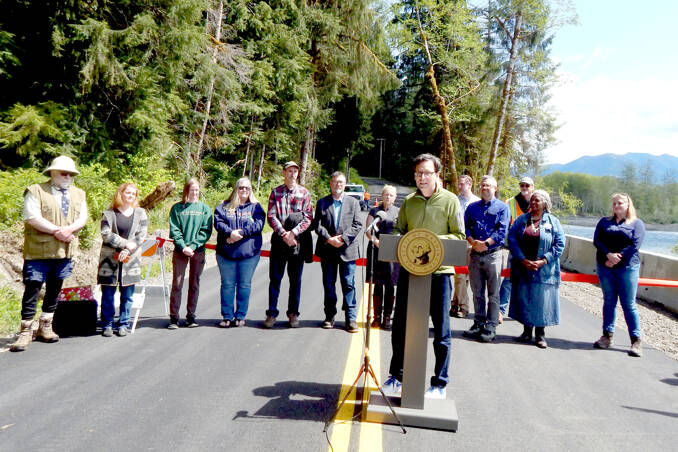 Gov. Bob Ferguson addresses the crowd at the Upper Hoh Road washout repair on Thursday afternoon. Local officials, business owners, contractors, workers from the Jefferson County Public Works department and a few individuals who donated funds to the project stand behind him. Before the ribbon was cut and the road officially opened, there were short statements from involved parties. Ferguson said he brought his hiking boots and joked that he wanted to be the first one to hit the trail. (Christi Baron/Olympic Peninsula News Group)