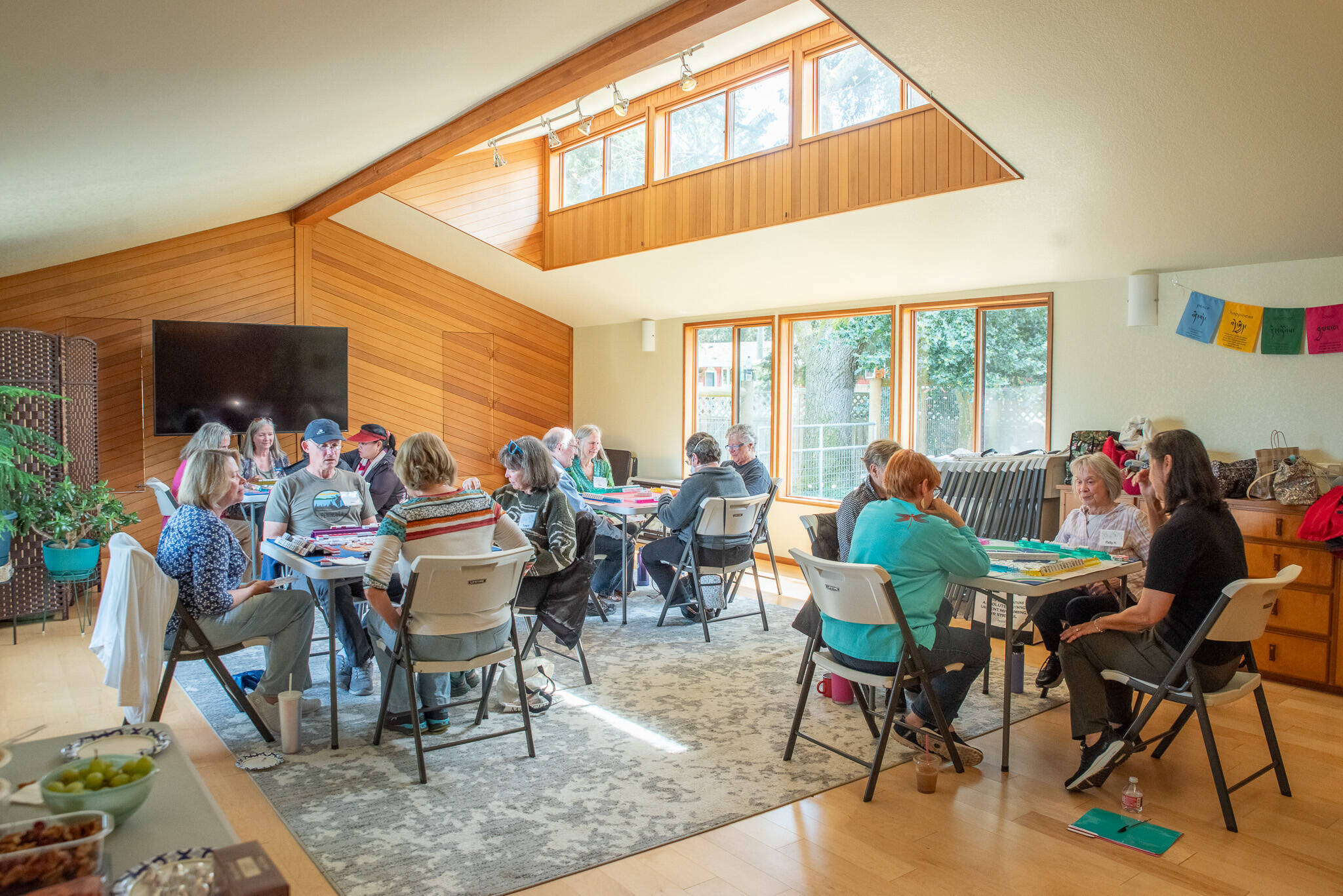 A group of people play American Mahjong at the Harmony Center of Sequim in the activities room, which is large and well-lit, with Wi-Fi, a 70-inch television, folding tables and chairs. (Emily Matthiessen/Olympic Peninsula News Group)