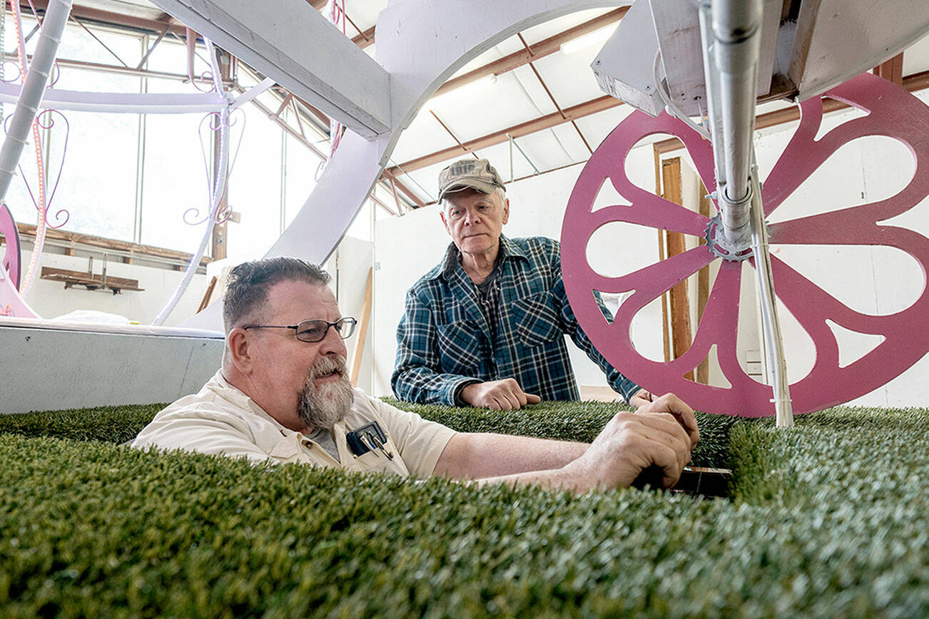 Bliss Morris of Chimacum, a float builder and driver of the Rhody float, sits in the driver’s seat on Thursday as he checks out sight lines in the 60-foot float he will be piloting in the streets of Port Townsend during the upcoming 90th Rhody Parade on Saturday. Rhody volunteer Mike Ridgway of Port Townsend looks on. (Steve Mullensky/for Peninsula Daily News)