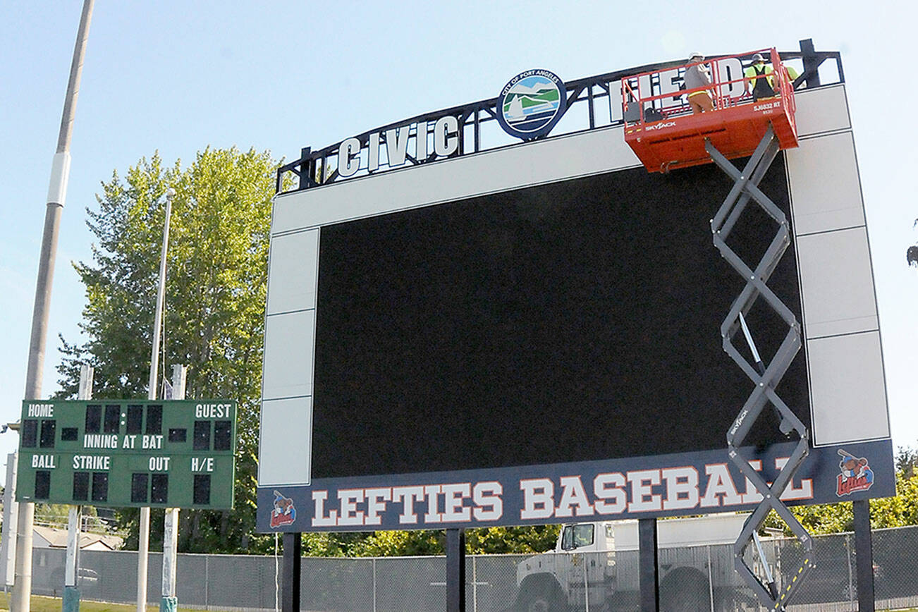 KEITH THORPE/PENINSULA DAILY NEWS
A crew from Olympic Electric installs a new scoreboard at Port Angeles Civic Field on Tuesday. The Port Angeles Lefties begin their 2025 West Coast League season at 6:35 p.m. Friday against Kamloops. The old scoreboard on the left is coming down and will be donated.