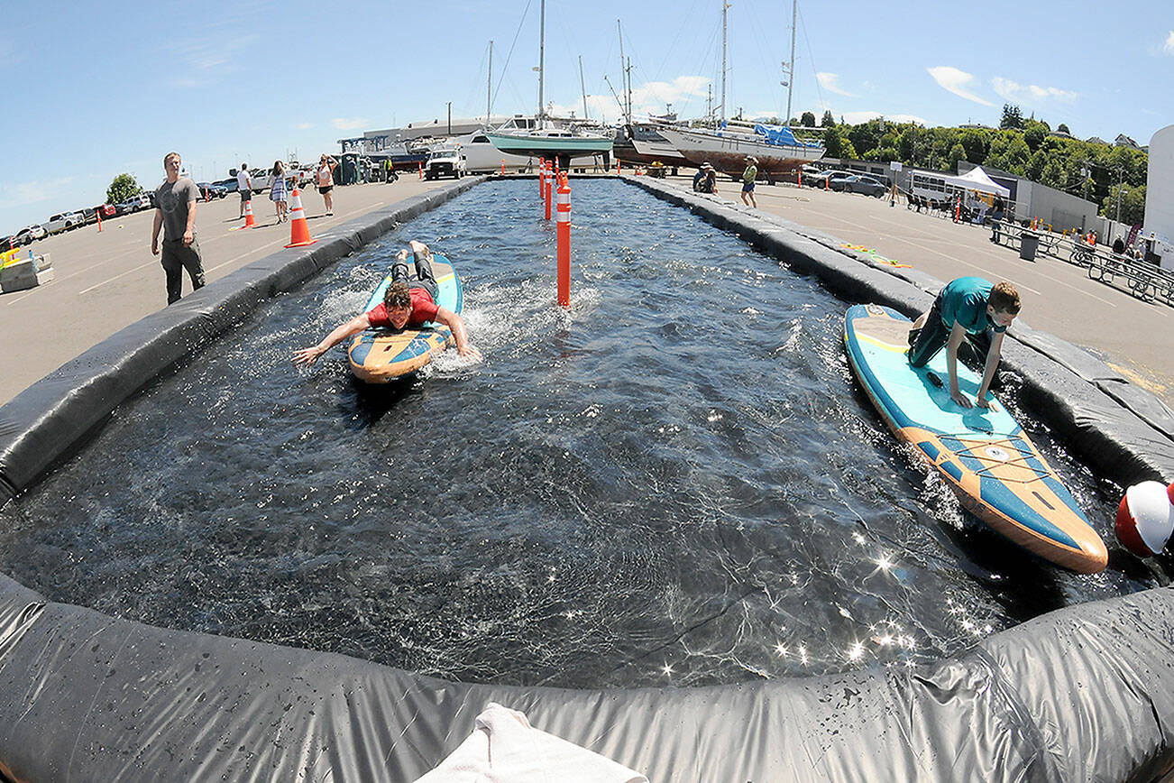 Ethan Davidson, 16, left, competes with his brother, Pierce Davidson, 12, both of Dallas, Texas, in a paddleboard race on a temporary course set up at East Boat Haven in Port Angeles as part of the weekend’s Maritime Career Fair & Festival. The two-day event, hosted by the Port of Port Angeles, featured informational displays, children’s activities, maritime demonstrations, food, music and a fishing derby. (Keith Thorpe/Peninsula Daily News)
