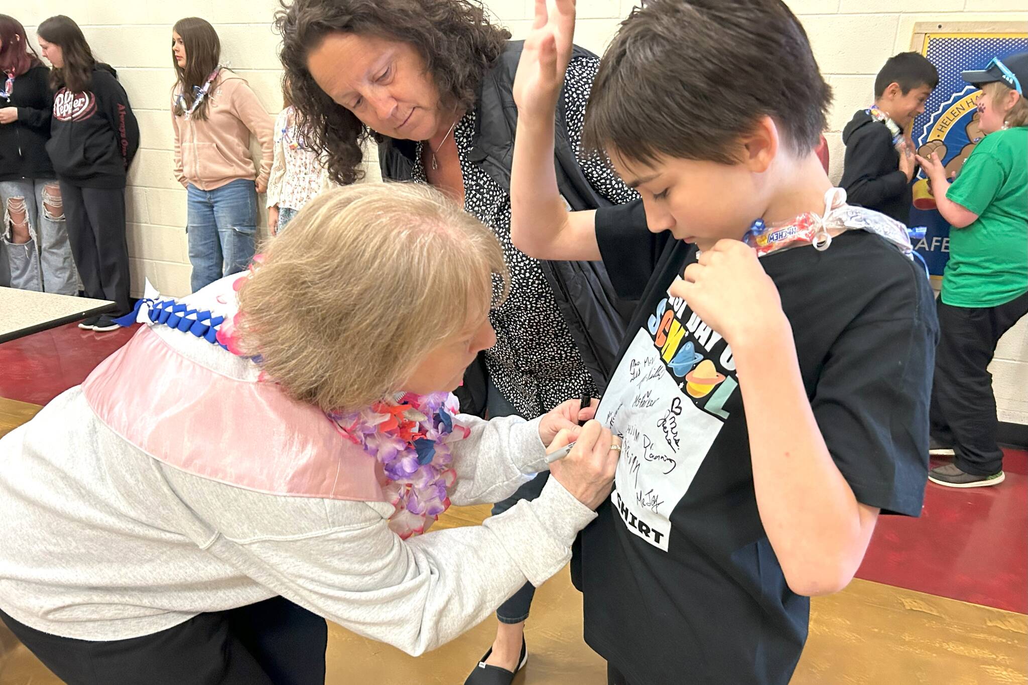 Reading Specialist Christine MacDougall Danielson signs fifth-grader Orion Schmit’s “last day of school” shirt with help from paraeducator Elizabeth Joers. (Matthew Nash/Olympic Peninsula News Group)