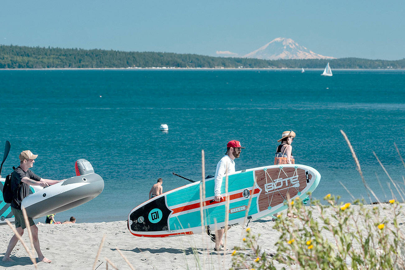 Beachgoers look for a spot on the sand on Sunday afternoon at Fort Worden State Park in Port Townsend. Mount Rainier looms in the distance. (Steve Mullensky/for Peninsula Daily News)