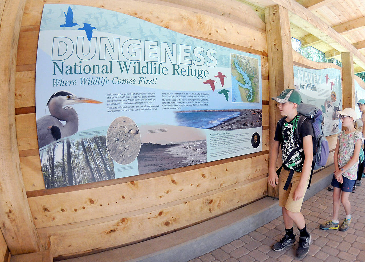 Marius Gerber, 13, front, and his sister, Tirza Gerber, 12, both of Zurich, Switzerland, examine information boards after a hike on Tuesday at the Dungeness National Wildlife Refuge northwest of Sequim. The main trail through the refuge provides access to Dungeness Spit and Dungeness Bay. (Keith Thorpe/Peninsula Daily News)