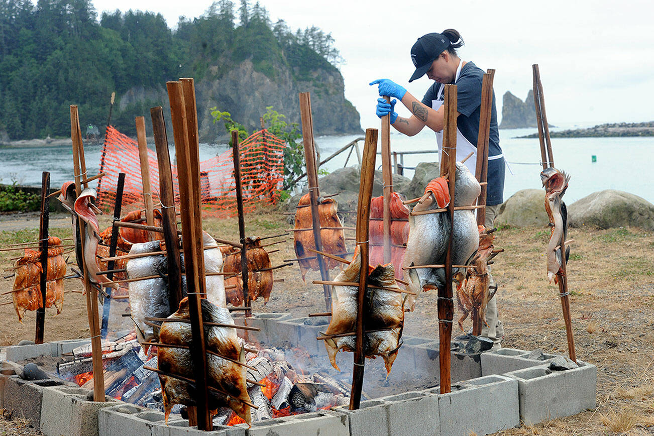 With the Quillayute River flowing toward James Island and the Pacific Ocean, Quileute tribal member Smokey Ward prepares baked salmon in the traditional way Saturday morning during the Quileute Days celebration in La Push. A large crowd gathered for the festival. (Lonnie Archibald/for Peninsula Daily News)