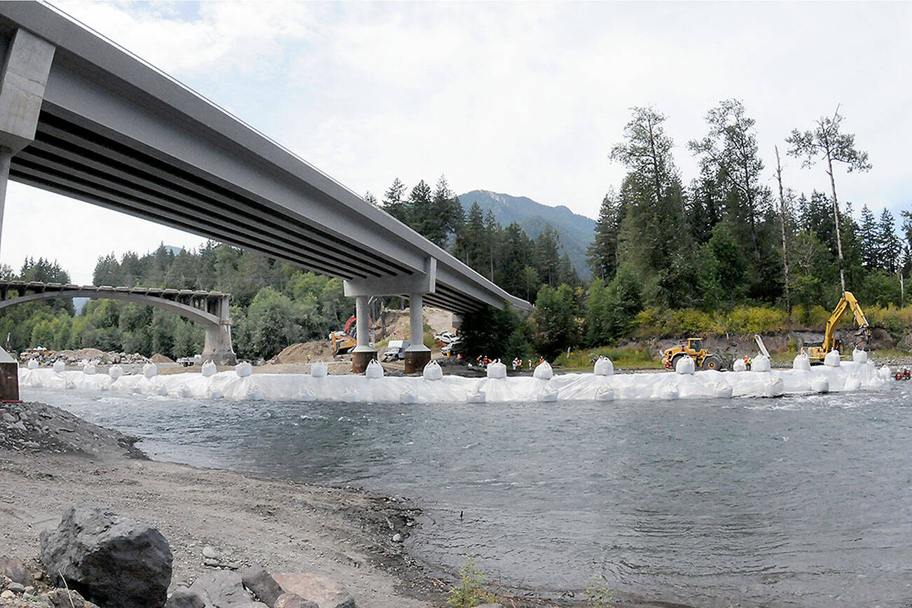 A state Department of Transportation crew constructs a temporary diversion dam under the former and current U.S. Highway 101 bridges on Saturday in preparation for the demolition of the old bridge. (Keith Thorpe/Peninsula Daily News)