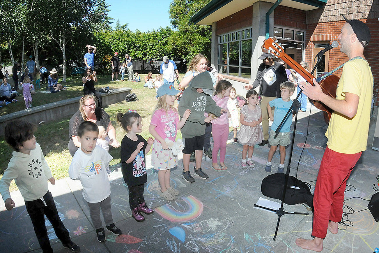 Youngsters gather on the lawn of the Port Angeles Public Library to listen to children’s entertainer Eli Rosenblatt of Seattle as part of the Port Angeles Parks and Recreation Department’s citywide Day of Play. The Saturday event featured a variety of activities for children and their parents at venues across the city. (Keith Thorpe/Peninsula Daily News)