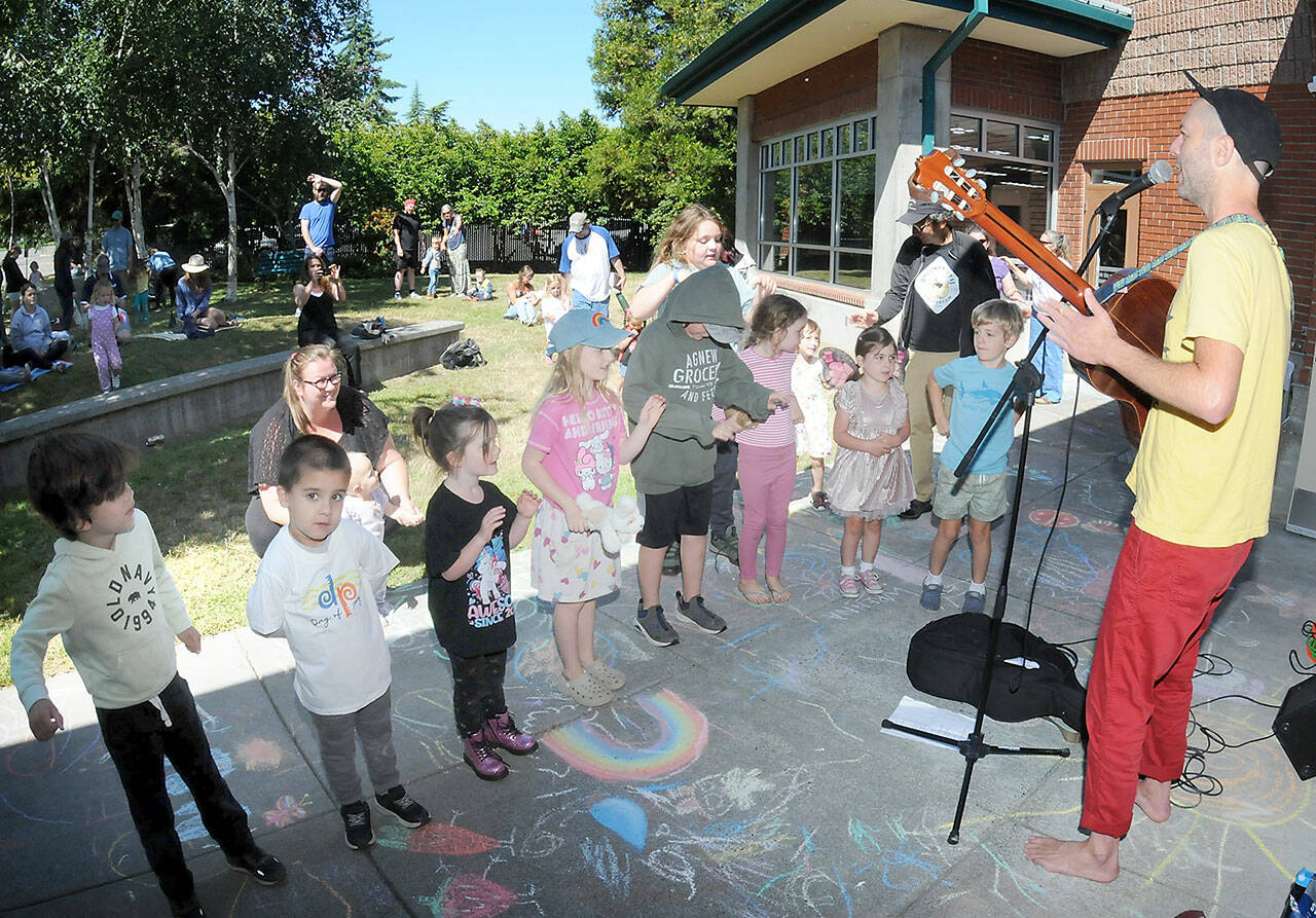 Youngsters gather on the lawn of the Port Angeles Public Library to listen to children’s entertainer Eli Rosenblatt of Seattle as part of the Port Angeles Parks and Recreation Department’s citywide Day of Play. The Saturday event featured a variety of activities for children and their parents at venues across the city. (Keith Thorpe/Peninsula Daily News)