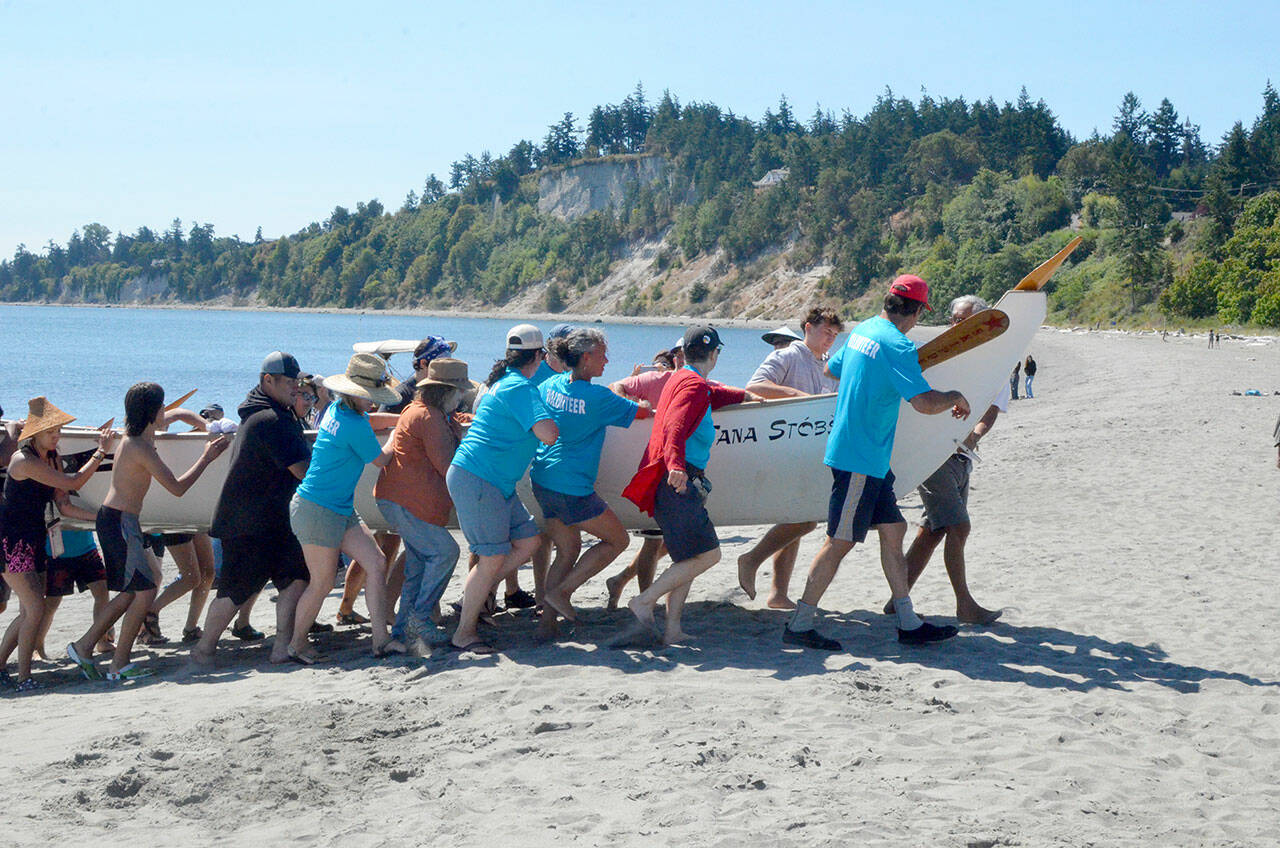 The Tana Stobs canoe, a family memorial canoe with members from the Port Gamble and Suquamish tribes, arrived first to the beach at Fort Worden on Tuesday. The canoe, in its 25th year, honors the memory of paddler Nic Armstrong’s brother Santana Ives. Their trip from Port Gamble took 4 1/2 hours. (Elijah Sussman/Peninsula Daily News)