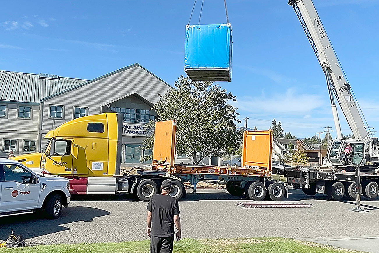 Workers with A&R Solar, Millican Crane Service and Trane Technologies guide a battery energy storage system into place Friday at the Port Angeles Senior Center. The city received a $450,000 grant from the state Department of Commerce to install the battery system and a solar array — solar cells wired together to create energy — to provide heating and cooling in case of a power outage. (Paula Hunt/Peninsula Daily News)