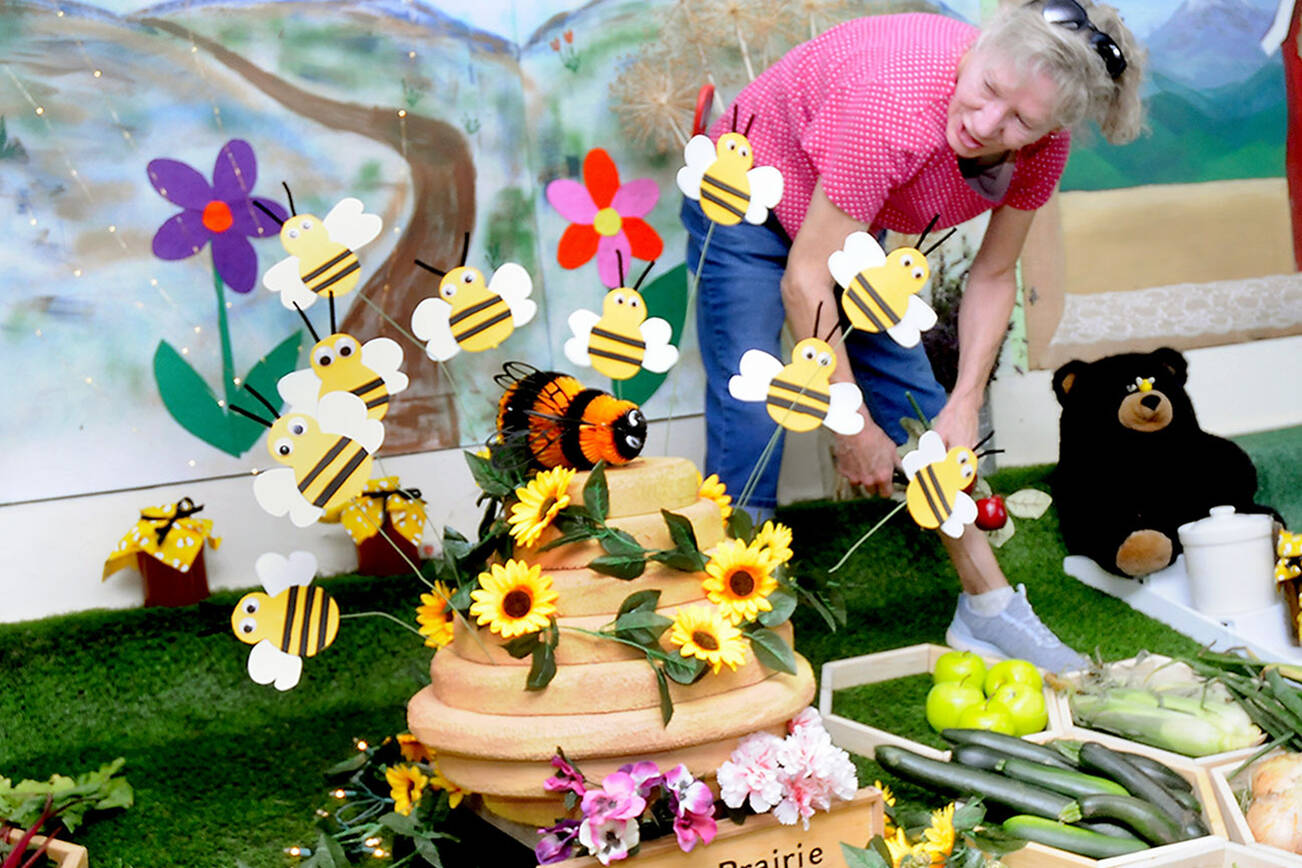 Terri Johnson of Sequim, a member of Sequim Prairie Grange No. 1108, puts the finishing touches on her organization’s display entry on Wednesday at the Clallam County Fairgrounds in Port Angeles. The display follows this year’s fair theme, “Bee-lieve in the Magic of the Fair.” The fair begins its four-day run today with agricultural judging, food, entertainment and other activities. (Keith Thorpe/Peninsula Daily News)