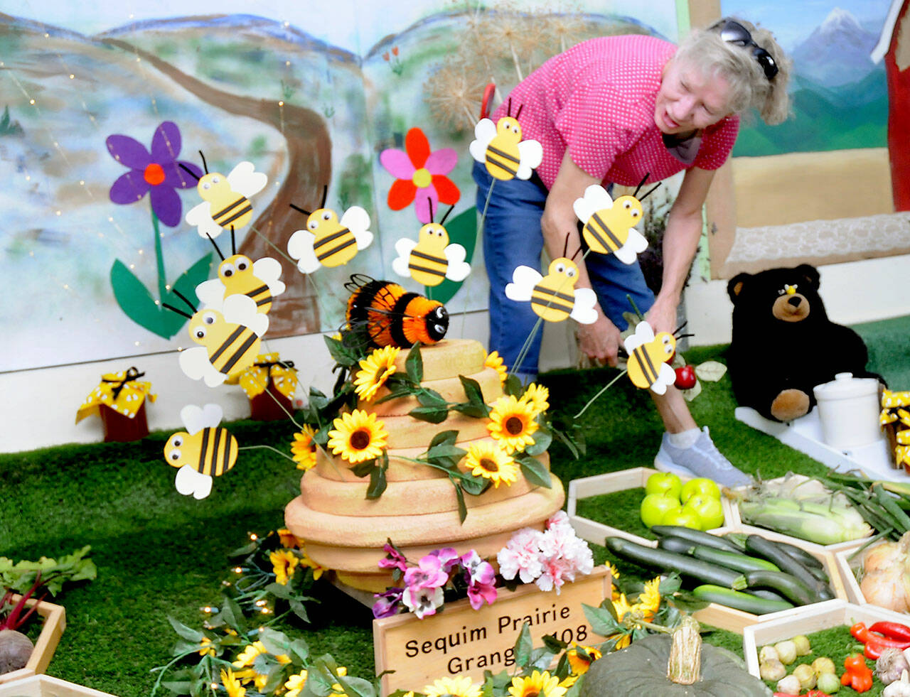 Terri Johnson of Sequim, a member of Sequim Prairie Grange No. 1108, puts the finishing touches on her organization’s display entry on Wednesday at the Clallam County Fairgrounds in Port Angeles. The display follows this year’s fair theme, “Bee-lieve in the Magic of the Fair.” The fair begins its four-day run today with agricultural judging, food, entertainment and other activities. (Keith Thorpe/Peninsula Daily News)