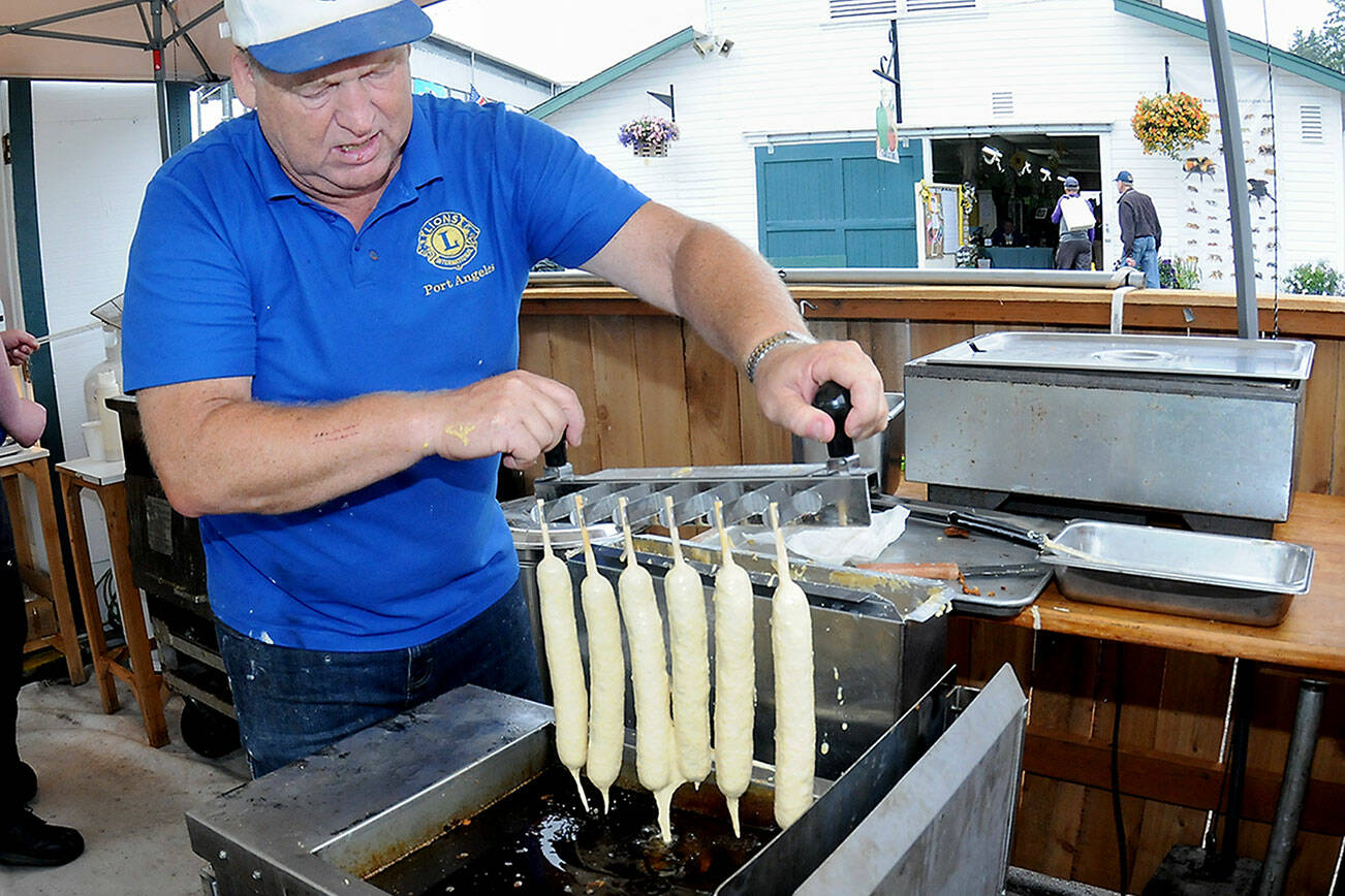 Port Angeles Lions Club member Kevin Borde dips batter-coated jumbo hot dogs into a fryer to make corn dogs at the club’s food stand at the Clallam County Fair on Friday. (Keith Thorpe/Peninsula Daily News)