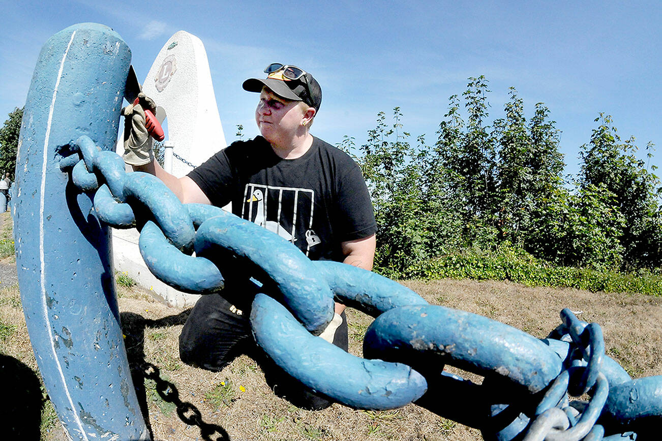 Port Angeles Parks and Recreation Department employee Jessica Adams scrapes off flaking paint from a bollard along the parking area at Haynes Viewpoint on Thursday in Port Angeles. Adams said the bollards and adjoining guard chains are scheduled for future repainting. (Keith Thorpe/Peninsula Daily News)