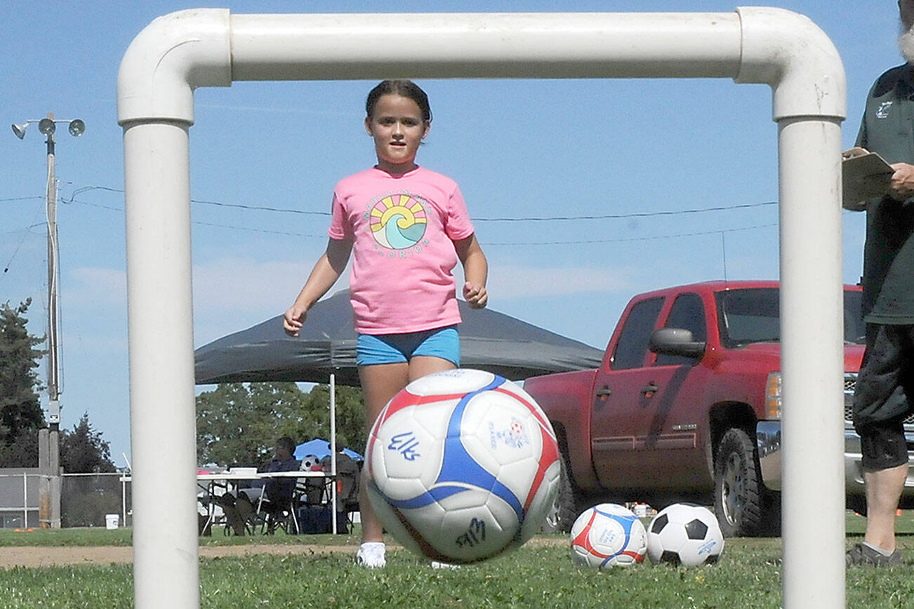 Kyra Toner, 8, of Burien kicks a soccer ball through a narrow goal as part of an informal soccer skills test during Saturday’s Party at the Park at Elks Playfield in Port Angeles. The event, hosted by the Port Angeles Naval Elks Lodge, featured a variety of activities for children and adults, food and live music. (Keith Thorpe/Peninsula Daily News)