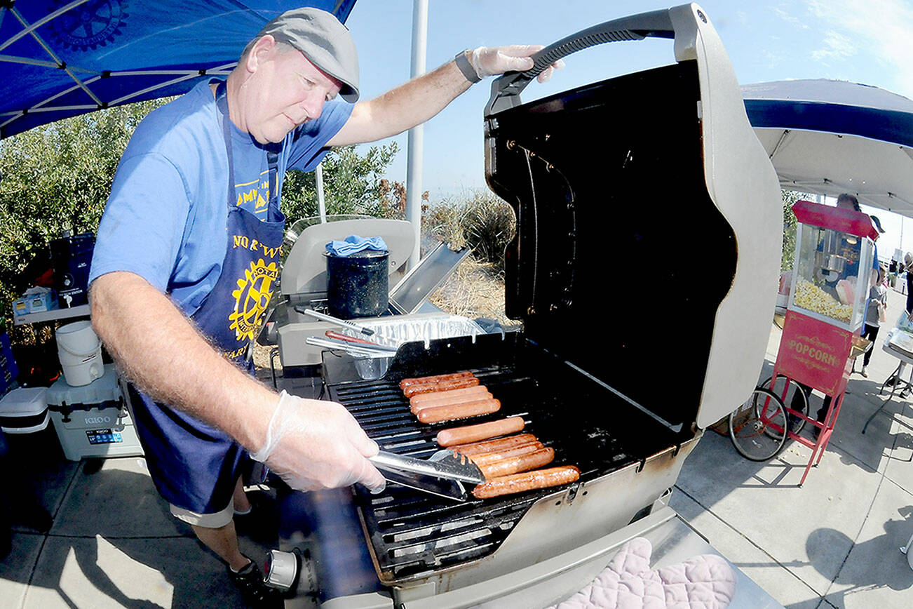 Chris Szczetczynski, president of the Nor’Wester Rotary Club, cooks hot dogs for festival-goers during Saturday’s Jammin’ in the Park at Pebble Beach Park in Port Angeles. The event, hosted by the Rotary Club and Koenig Subaru, featured an afternoon of music, a car show, food and children’s activities. (Keith Thorpe/Peninsula Daily News)