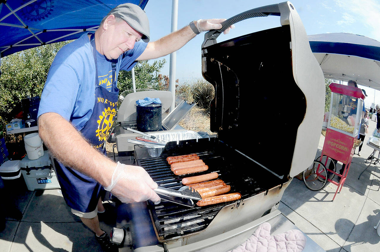Chris Szczetczynski, president of the Nor’Wester Rotary Club, cooks hot dogs for festival-goers during Saturday’s Jammin’ in the Park at Pebble Beach Park in Port Angeles. The event, hosted by the Rotary Club and Koenig Subaru, featured an afternoon of music, a car show, food and children’s activities. (Keith Thorpe/Peninsula Daily News)