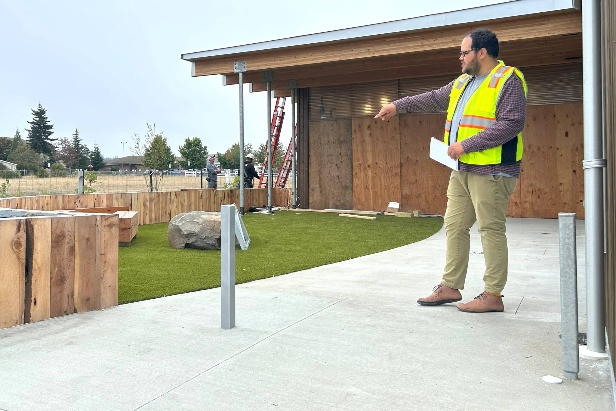 North Olympic Library System Executive Director Noah Glaude gestures to the outdoor children’s area of the Sequim Library, which features benches, a rock and bouncy turf along with a soon-to-be installed gate and a door directly into the inside children’s area. (Matthew Nash/Olympic Peninsula News Group)