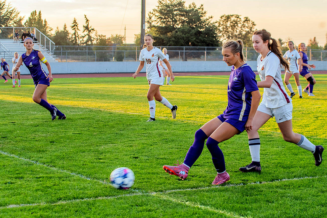Sequim’s Kiley Winter sends a pass upfield as teammate Rainey Brewer, far left, looks on during the Wolves’ season-opener against Kingston on Thursday. Winter scored a goal for Sequim, but the Buccaneers came out on top 2-1 in the Olympic League contest. The Wolves host North Mason at 7 p.m. Tuesday. (Emily Matthiessen/for Peninsula Daily News)