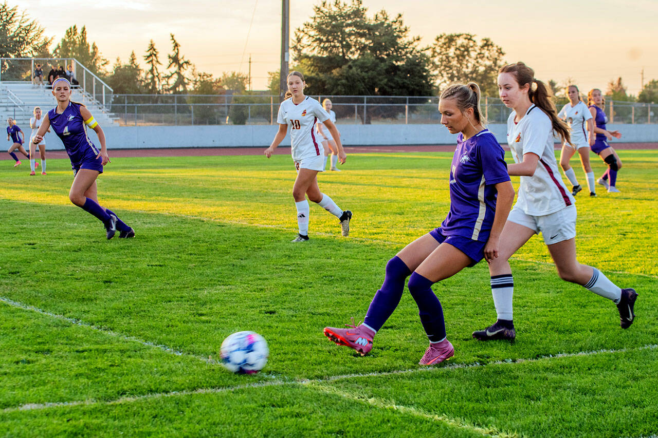 Sequim’s Kiley Winter sends a pass upfield as teammate Rainey Brewer, far left, looks on during the Wolves’ season-opener against Kingston on Thursday. Winter scored a goal for Sequim, but the Buccaneers came out on top 2-1 in the Olympic League contest. The Wolves host North Mason at 7 p.m. Tuesday. (Emily Matthiessen/for Peninsula Daily News)
