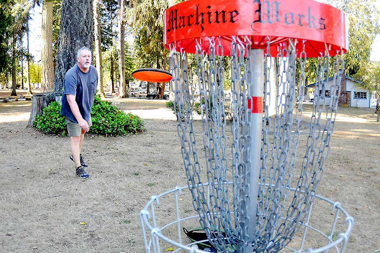 Michael Thill of Boquete, Panama, formerly of Sequim, practices his putts at the disc golf course on Thursday at Lincoln Park in Port Angeles. The park features a full 18-hole course for disc golf enthusiasts. (Keith Thorpe/Peninsula Daily News)