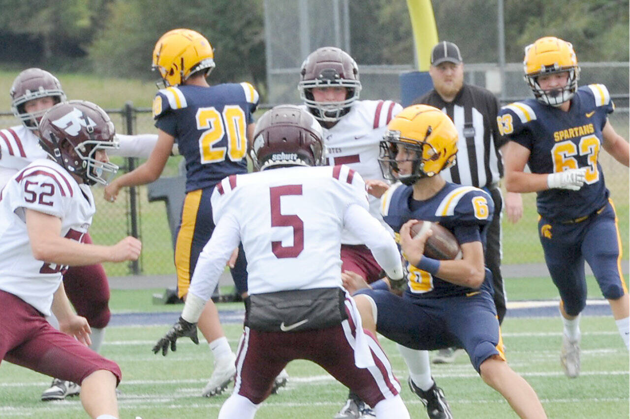 Forks quarterback Lane Helvey looks for room to run the ball against Kittitas on Saturday in Forks. (Lonnie Archibald/for Peninsula Daily News)