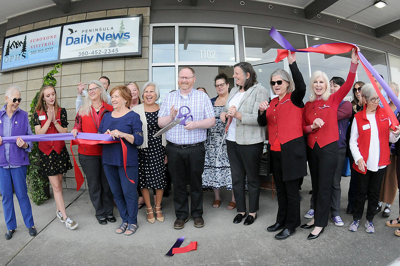Peninsula Daily News Editor Brian McLean and Publisher Eran Kennedy cut ceremonial ribbons on Thursday in front of the newspaper’s new building at 1102 E. First St. in Port Angeles. Newspaper employees and ambassadors from both the Port Angeles and Sequim-Dungeness chambers of commerce celebrated the event. (Peninsula Daily News)