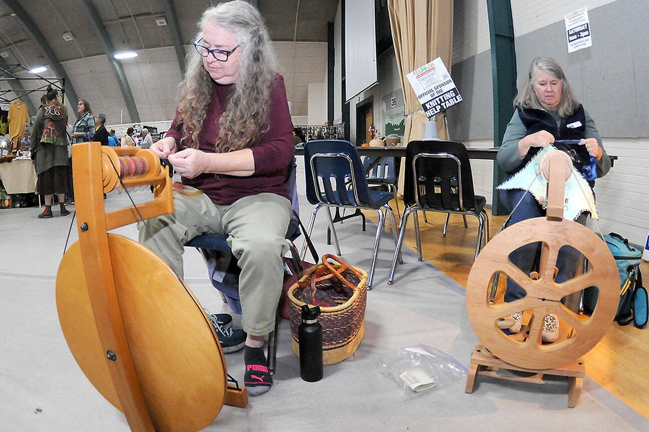 Sarah Severns, left, and Diana Burns, both of Sequim and members of the North Olympic Shuttle & Spindle Guild, operate a pair of spinning wheels at a demonstration table at the Pacific Northwest Fiber Arts Expo on Friday at Vern Burton Community Center in Port Angeles. The three-day festival featured dozens of vendor displays, workshops and demonstrations that supported knitting, weaving and other fiber activities. (Keith Thorpe/Peninsula Daily News)