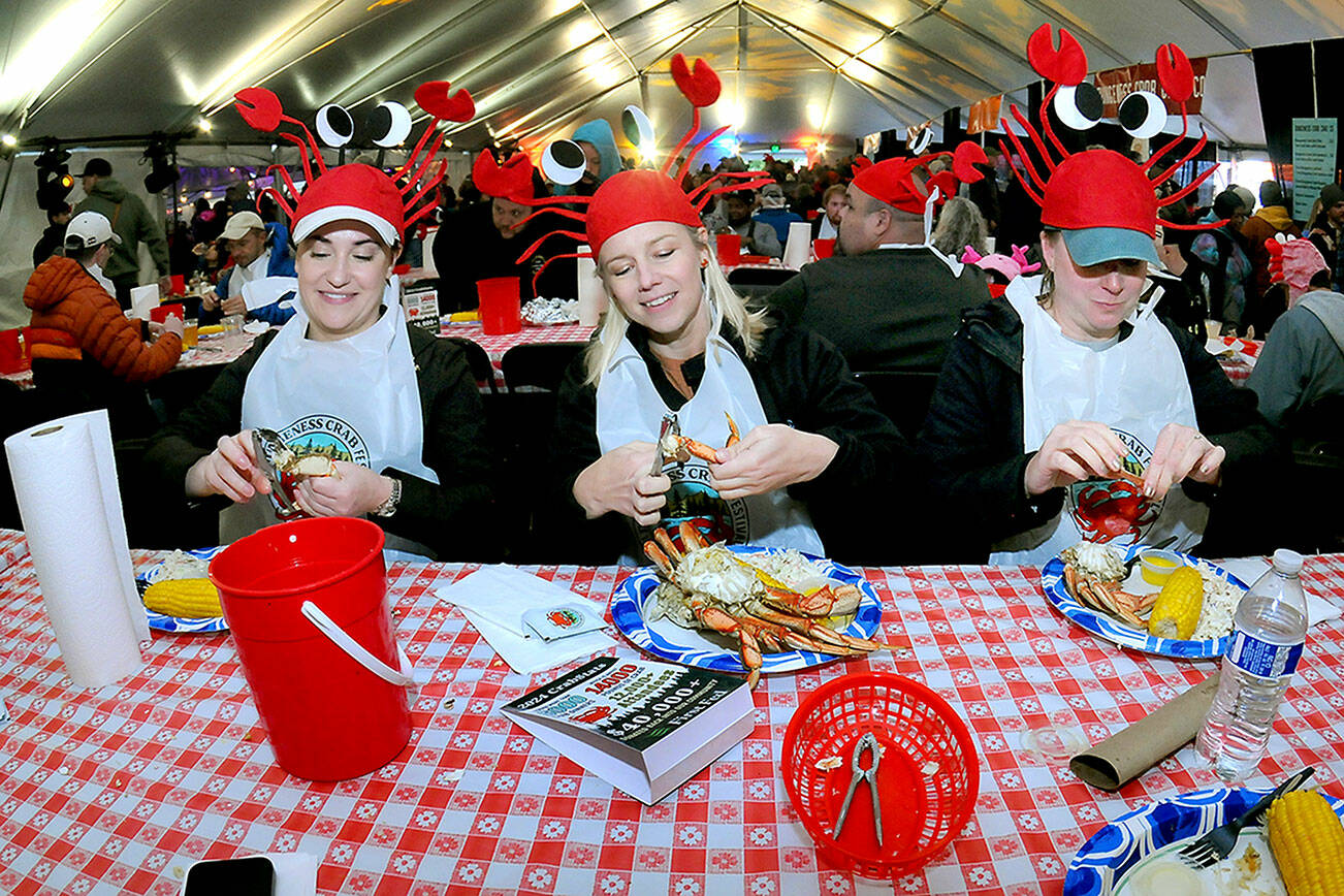 Festival-goers, from left, Cara Saunto, Shelby Damiani and Adrienne Bohannon, all of Seattle, crack into their crab dinners on Saturday at the Dungeness Crab Festival on the Port Angeles waterfront. The annual event drew thousands of visitors to downtown Port Angeles for a variety of seafood delights, music, cooking demonstrations, a craft fair and other activities. (Keith Thorpe/Peninsula Daily News)