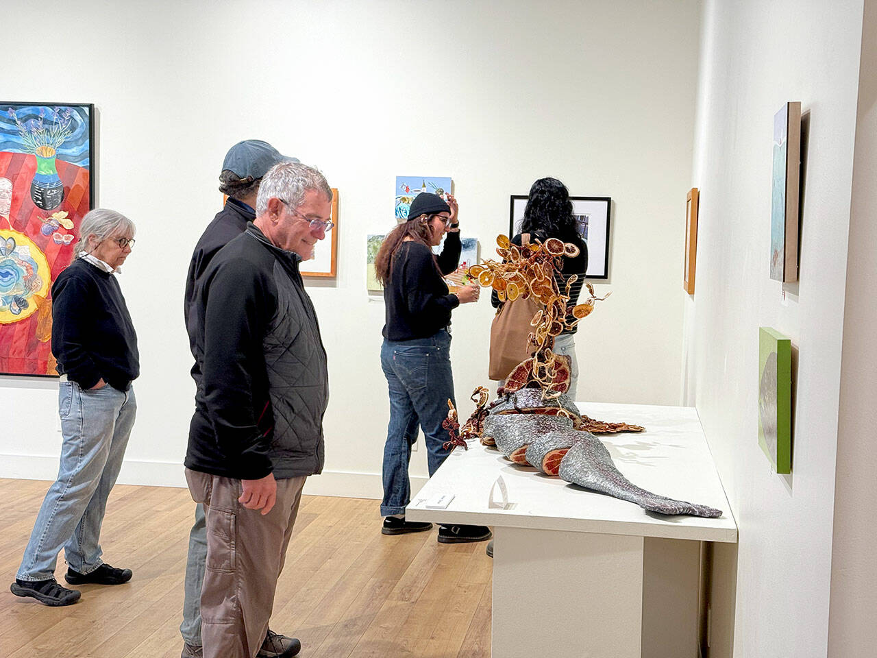 Jeanette Best Gallery visitors check out Ali Whitmore’s “Entree — Stuffed Whole Trout” during Art Walk. The sculpture won the Jurors’ Choice and People’s Choice awards in the recent “Potluck Banquet” exhibition. (Diane Urbani/Northwind Art)