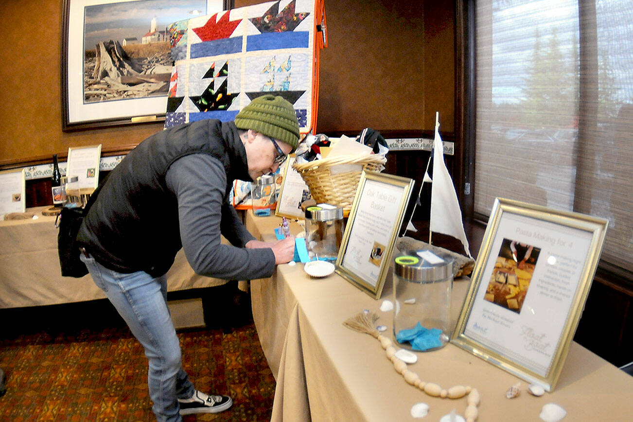 Rachel Anderson of Port Angeles fills out a raffle ticket for gifts and nautical-themed items during Wednesday’s Float the Boat fundraiser benefitting the Port Angeles junior and senior high school sailing teams. The event, held at Olympic Lodge by Ayres in Port Angeles, was conducted by the nonprofit Community Boating Program to support youth sailing and other nautical programs. (Keith Thorpe/Peninsula Daily News)