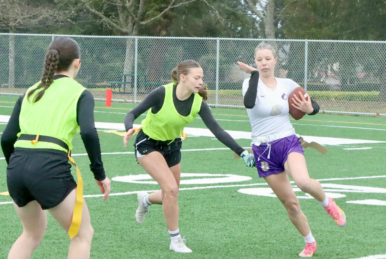 In a scrimmage last between the new Port Angeles and Sequim flag football squads, Sequim's Lily Sparks tries to avoid having her flag pulled by Port Angeles defender Audrey Rudd. On the left is Port Angeles' Miriam Cobb. (Dave Logan/for Peninsula Daily News)